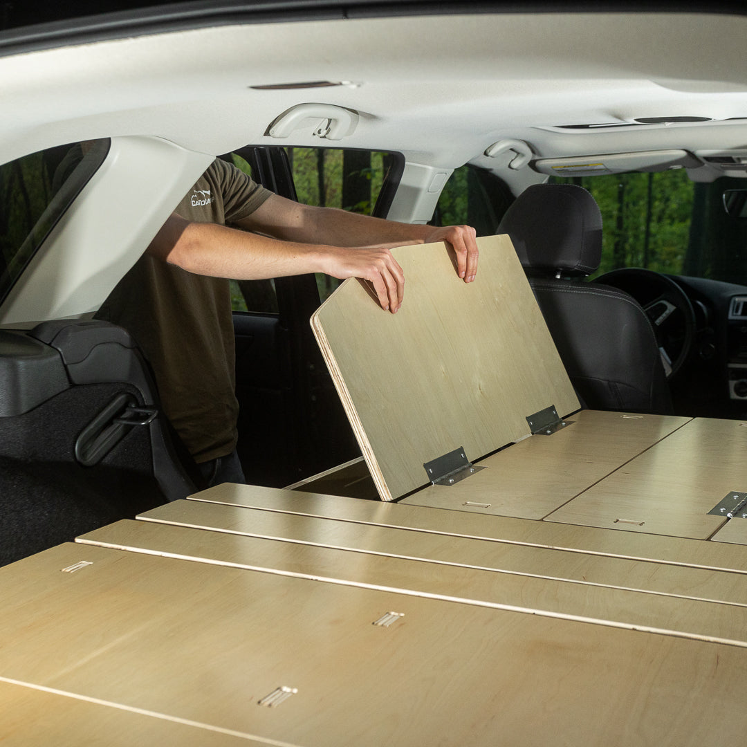 A person converting a CarToCamp Subaru Outback Sleeping Platform into a sleeping platform with extra storage space.