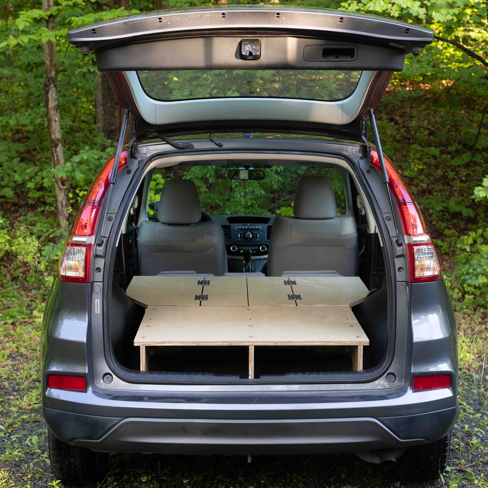 The trunk of a CarToCamp honda cr - v with a Sleeping Platform in it.